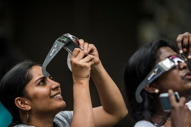 Deepthi Jayaprakas tries to photograph the solar eclipse with a smartphone through eclipse glasses during a total solar eclipse event at the Brookfield Public Library on August 21, 2017.